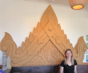 Staff member stands next to a decorative Cambodian carved panel at Banteay Srey Khmer Restaurant