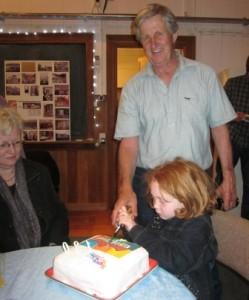 Roydon Hartsone cuts the Old School birthday cake helped by a young assistant