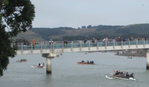 Waka head for the finish line under the gaze of spectators watching on the footbridge 